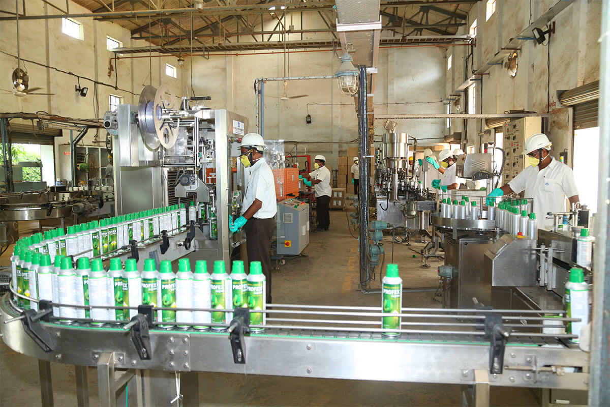Workers operating machinery on a bottling production line