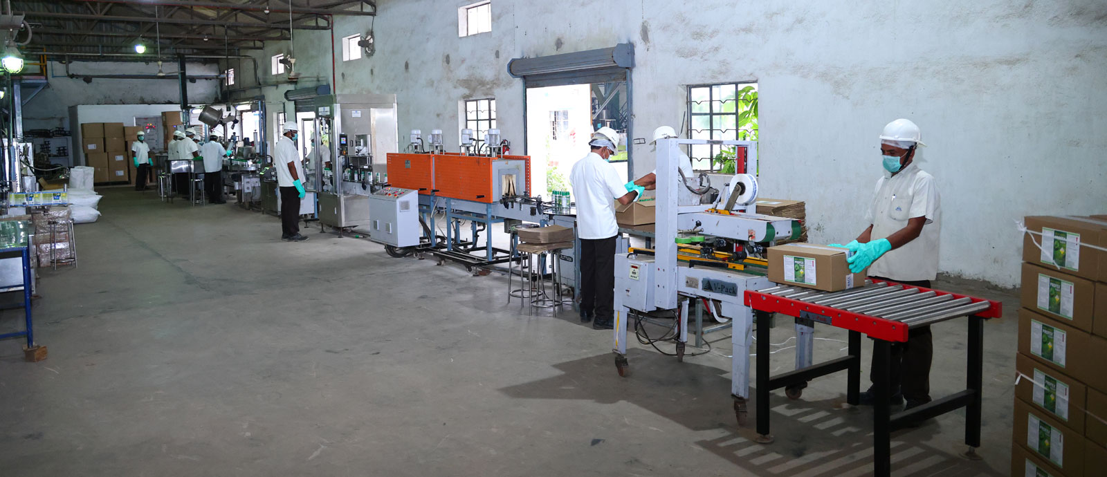 Workers in safety gear packaging products in an organized factory with conveyor belts